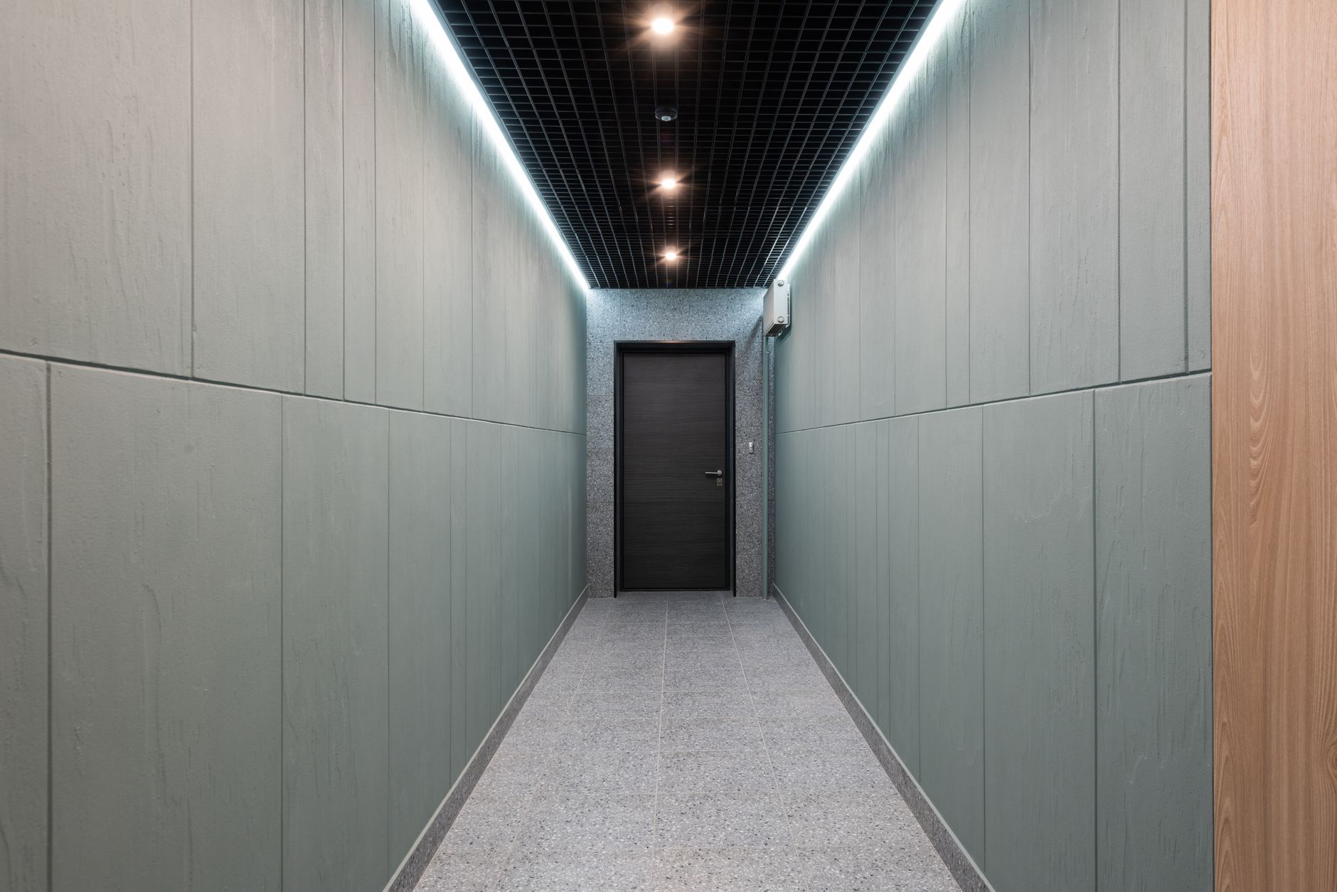 A lit building corridor leading to a secured door at the far end